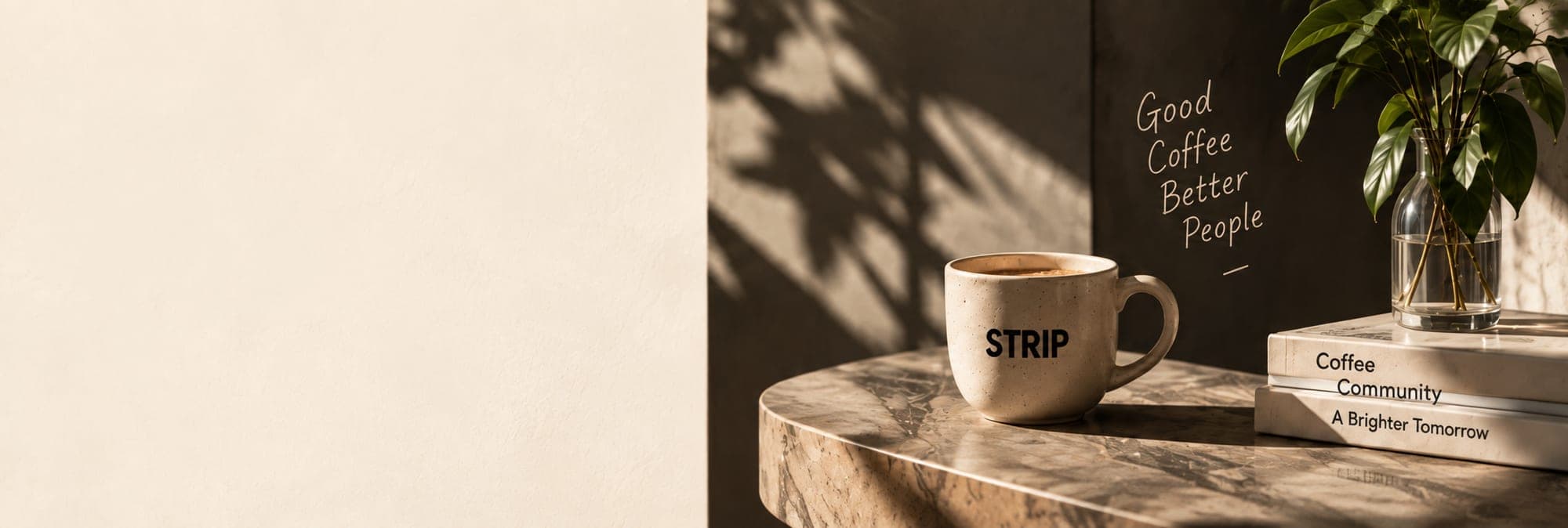 A STRIP cup on a marble table beside books and a vase of leaves